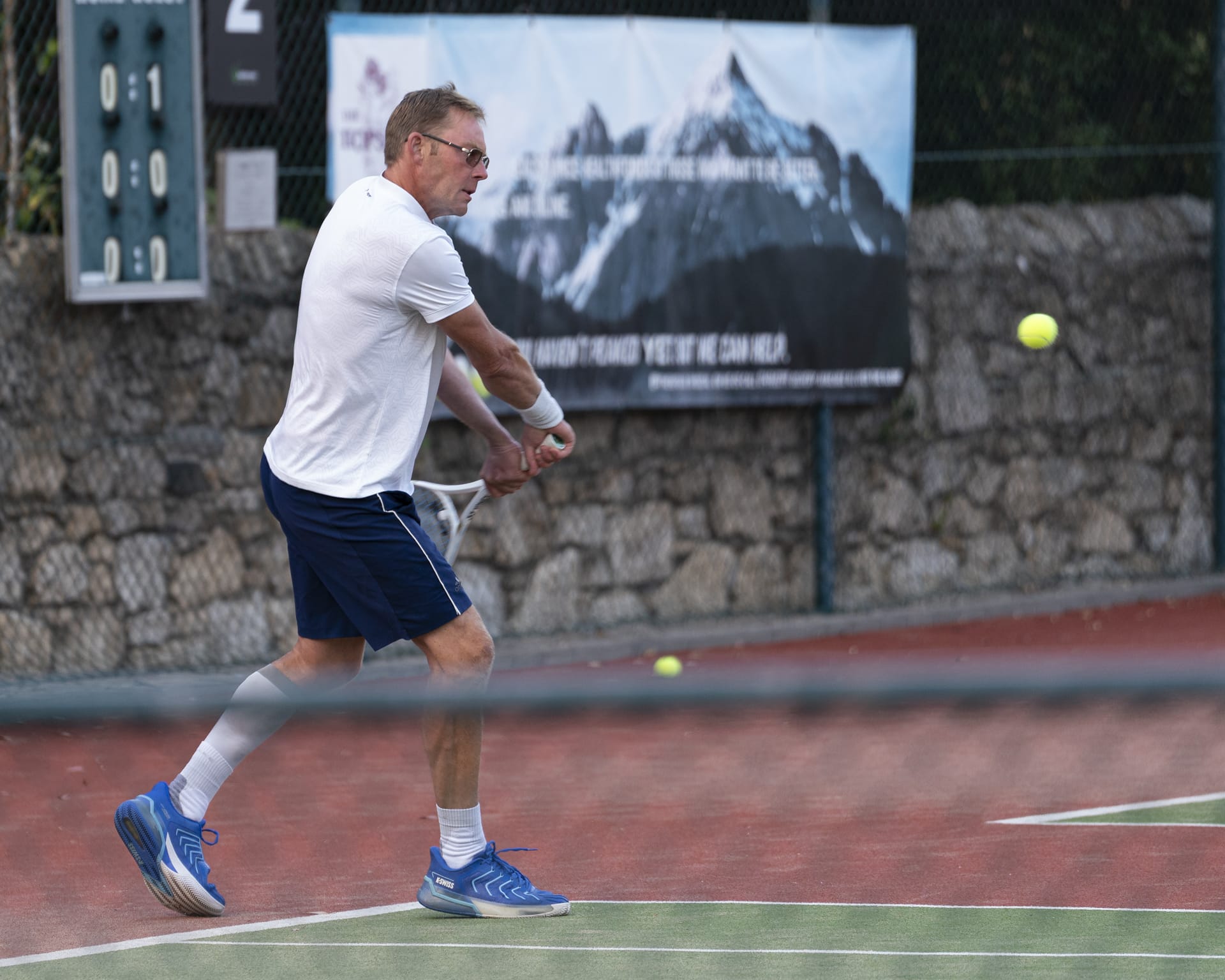 Artem playing a backhand on an outdoor tennis court.